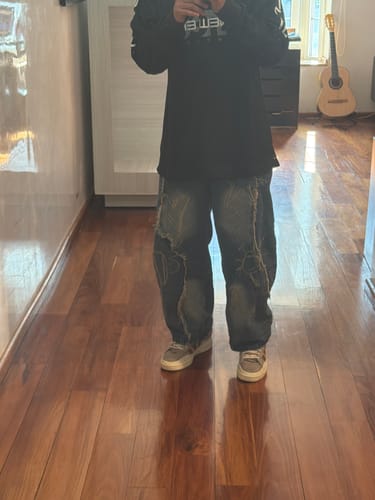 Customer standing indoors showing the baggy fit of the washed raw-edge jeans.