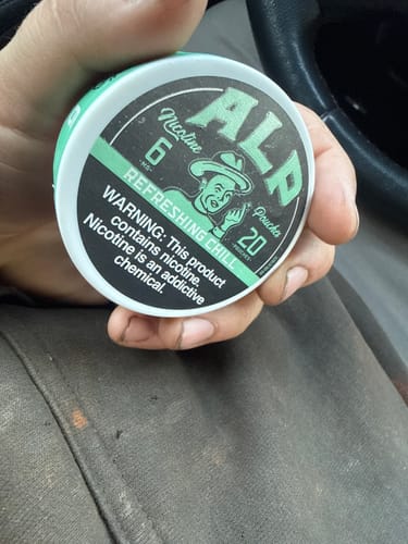 Customer holding a can of Refreshing Chill Nicotine Pouches in their hand inside a car.
