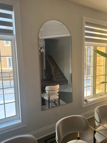 Customer's Gold Full Length Arch Mirror mounted on a dining room wall between two windows, reflecting a hallway.