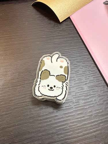 Customer's cute Cozy Pup Paper Clip featuring a cartoon dog lying on its back on a desk.