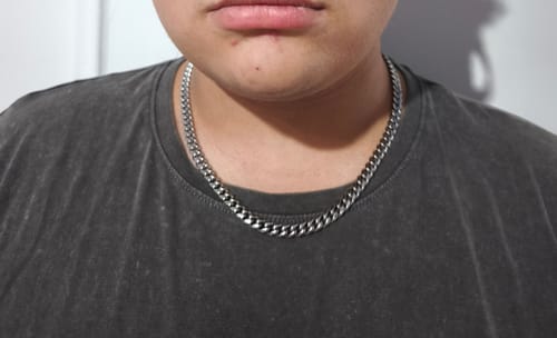 Primer plano de un cliente usando la Cadena Cuban Link de 8mm sobre una camiseta oscura.
