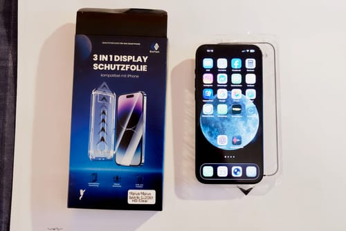 Ein Kunde zeigt die Verpackung der 3 in 1 Schutzfolie neben einem iPhone in der Anbringhilfe.