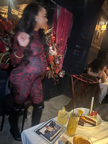 Reviewer showing a side view of the fit of the red and black Naked Print Closed Toe Jumpsuit while standing.