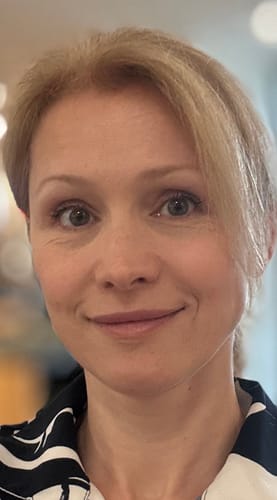 Reviewer shows a close-up of her face with makeup on while reviewing the Grass Fed Tallow & Manuka Honey Balm.