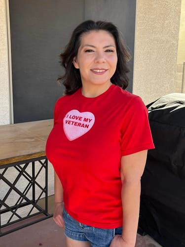 Customer smiling while wearing the red Love My Veteran Candy Heart t-shirt outdoors.