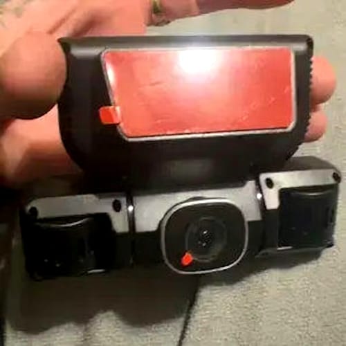 Customer holding the black 360° Dash Camera, showing its multiple lenses and red adhesive mount.