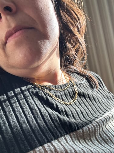 Close-up of a reviewer wearing the layered gold Maui Paperclip Necklace against a dark ribbed sweater.