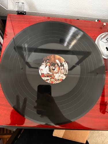 Customer's custom vinyl record on a red turntable. The center label shows a detailed photo of a group dinner.