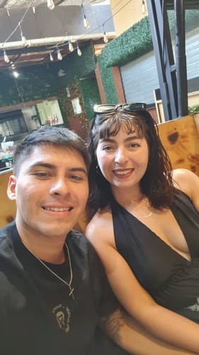 Cliente luciendo el Colgante Crucifijo sobre una camiseta negra, junto a su pareja.