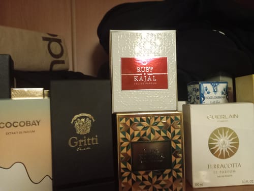 Recensore mostra la scatola bianca di Ruby eau de parfum in mezzo ad altre fragranze.