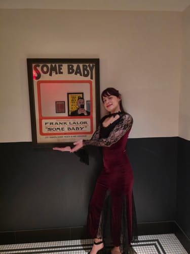 Reviewer wearing the red and black 1930s Lace Long Sleeve Fishtail Dress, posing indoors next to a framed picture.