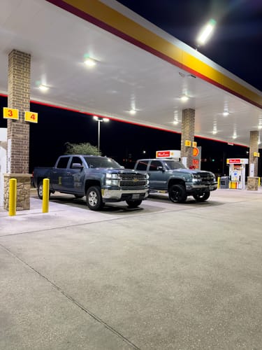 Customer's grey Silverado 1500 with the 3" Lift Kit installed, parked at a gas station at night.