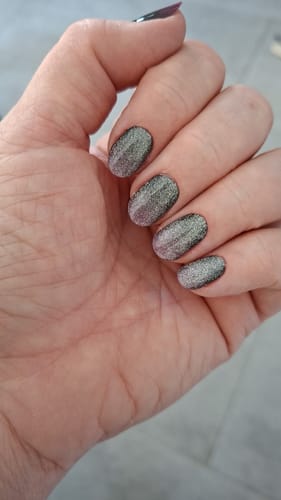 Hand einer Kundin, die die glitzernden Fuchsia Ombré Cateye UV-Gelfolien nach 10 Tagen Tragezeit zeigt.