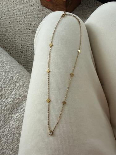 Reviewer's gold Clover Cutie Chain necklace displayed on a white surface, showing the small clover charms and round stone detail.