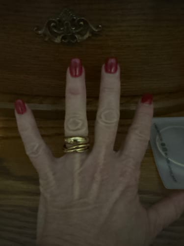 Customer's hand wearing the stacked gold Leilani Dome Ring on their middle finger.