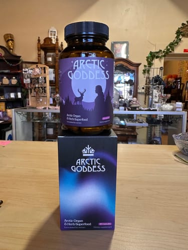 Customer's bottle of Arctic Goddess Reindeer Organ Superfood sitting on top of its box on a wooden counter.
