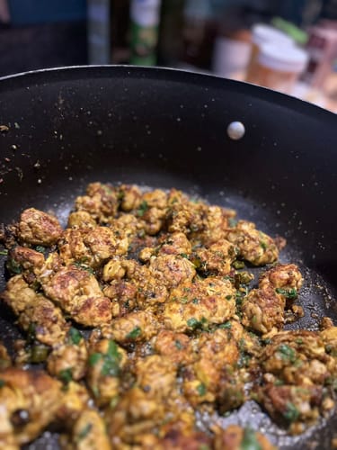 Close-up of a customer's seasoned Halal Omega-3 Chicken Breast cooking in a black pan.