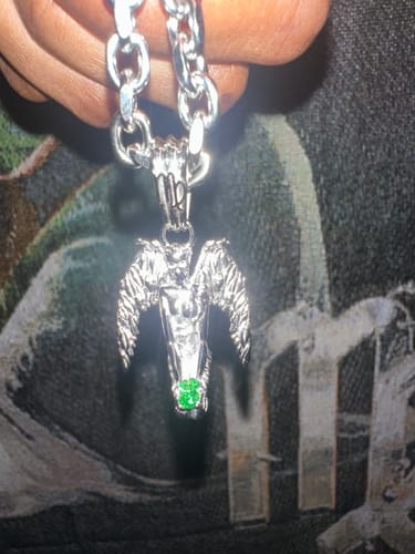 Customer holding their silver Virgo Zodiac Pendant, showing the detailed winged figure and green gem.