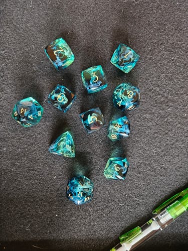 Customer's swirled URWizards D&D Resin Tidebound Fate dice set scattered across a dark surface.