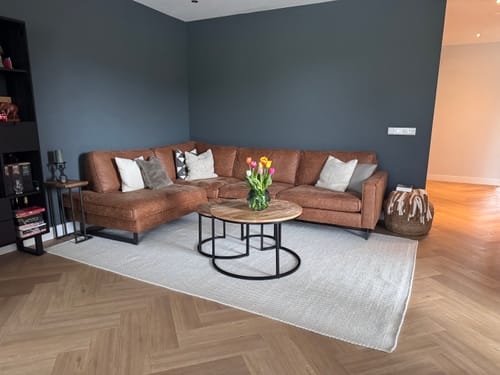 Recensentfoto van het witte by fonQ Chess Wollen Vloerkleed in een stijlvolle woonkamer met een bruine bank.