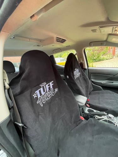 Customer's two black Waterproof Car Towel Seat Covers draped over the driver and passenger seats inside a car.