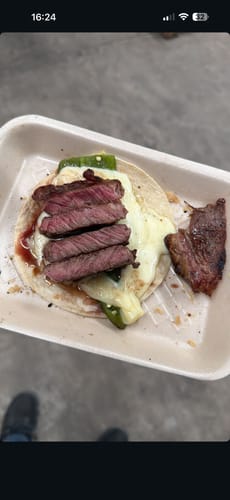 Primer plano de un taco preparado por un cliente con carne del Kit Carne Asada, queso derretido y chile.