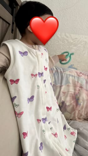 Reviewer's child wearing the white 4 Season Baby Sleep Bag with Feet with a colorful butterfly pattern.