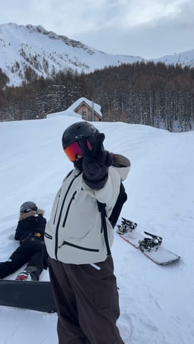 Reviewer on a snowy mountain wearing the light-colored Insulated Snow Jacket and making a peace sign.