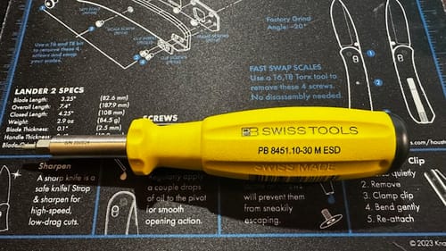 Reviewer's yellow PB Swiss ESD Bit Holder with a textured grip, shown on a schematic mat.