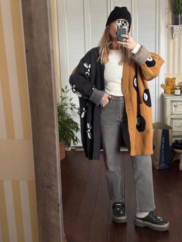 Reviewer in a mirror selfie showing the oversized fit of the split-color Balloon Dog & 8 Ball Cardigan.