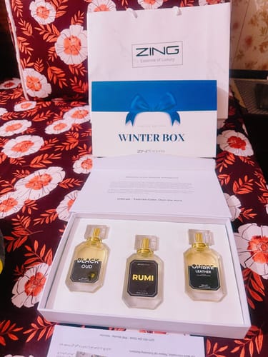 Customer's open 'WINTER BOX' perfume set with three bottles and a brand bag on a floral surface.