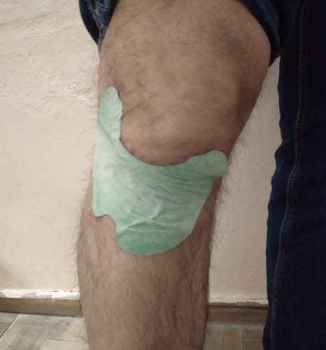 Primer plano del Parche para Rodilla verde de un cliente aplicado en su pierna.