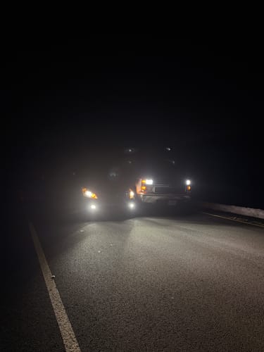 Customer's review photo comparing bright Carifex LED headlights on a truck to dimmer standard lights at night.
