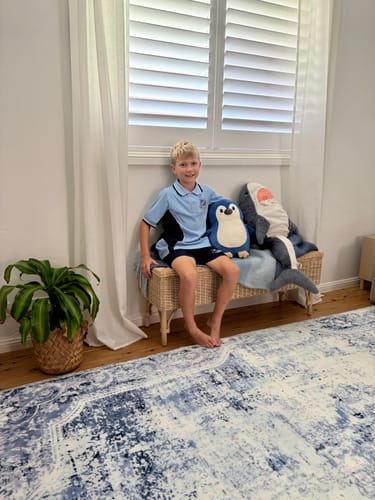 Customer's Mellow Mat v2® in Frosthaven print, laid out in a bright room with a child sitting on a bench in the background.