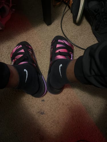 Reviewer's close-up of their feet wearing the Mystery DracoSlides with shiny pink and purple straps over black socks.