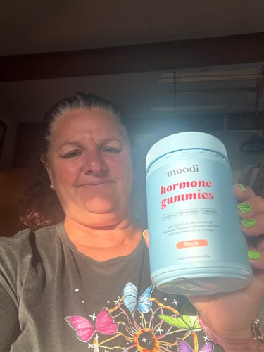 Reviewer holds up their light blue bottle of Peach Hormone Gummies.