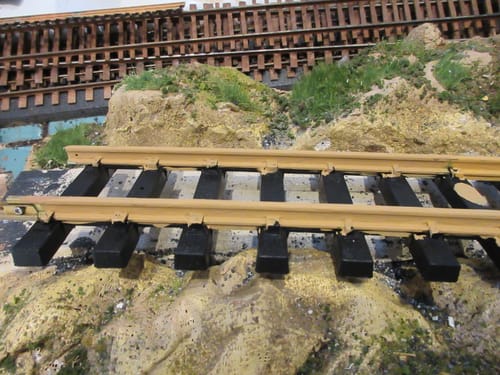 Reviewer shows model railroad rails painted with the dusty rust Mission Gold DET 685 paint.