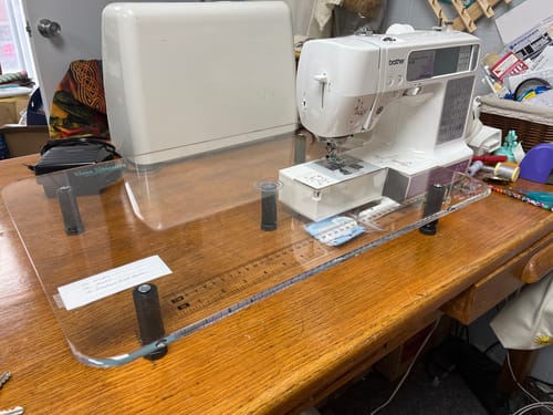 Customer's clear Sew Steady Extension Table fitted around a sewing machine on a wooden desk, expanding the work area.
