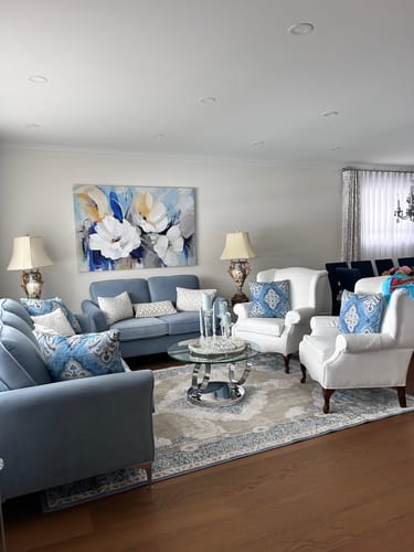 Reviewer's 'Abstract Flower' canvas on a living room wall, matching the blue sofas and white armchairs.