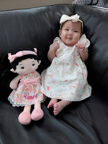 Customer's Personalized Princess Peony doll sitting on a couch beside a smiling baby.