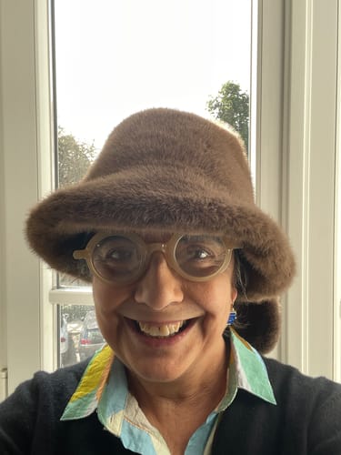 Customer smiling while wearing the brown, plush bucket hat with rabbit ear design.