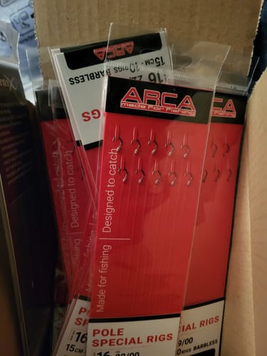 Recensent toont meerdere verpakkingen van de POLE SPECIAL BARBLESS RIG in hun rode verpakking.