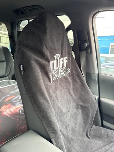 Customer's dark grey Waterproof Car Towel Seat Cover installed on the front seat of a car, showing the logo.