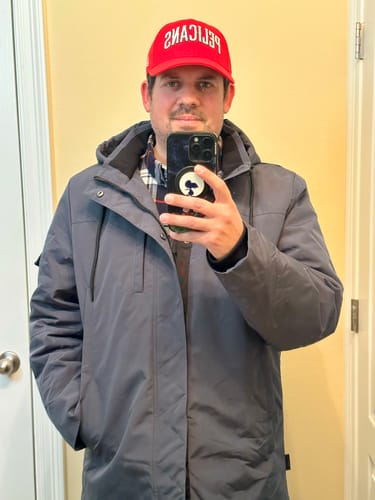 Reviewer wearing the slate Parka "Slate" with the hood up while taking a mirror selfie indoors.
