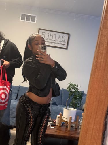 Reviewer in a mirror selfie showing the fit of the black denim Low Risers with lace-up legs.