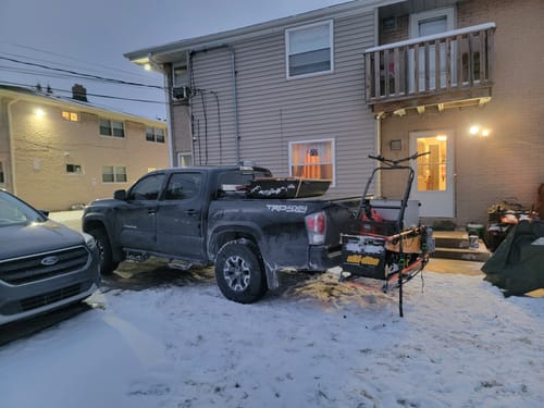 Customer's loaded Toyota Tacoma parked in snow, showing minimal rear squat with gear in the bed and on a hitch carrier.