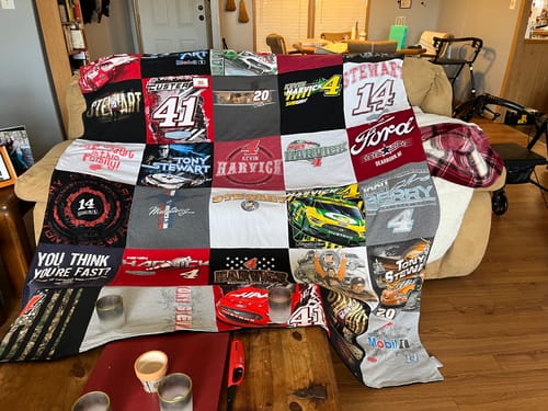 Customer's colorful Premium T Shirt Quilt with a racing theme draped over a living room couch.
