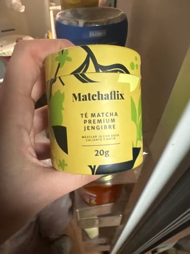Un cliente sostiene el bote amarillo de Té Matcha Premium Jengibre en la mano.