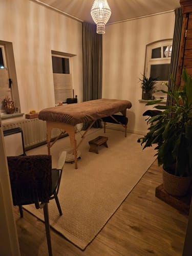 Klant toont het witte, wollen by fonQ Chess vloerkleed in een sfeervolle praktijkruimte.