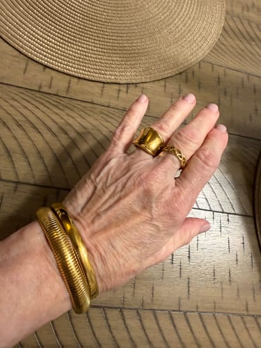 Customer wearing the stacked gold Ibiza Chunky Bangle bundle on their wrist, along with two rings.